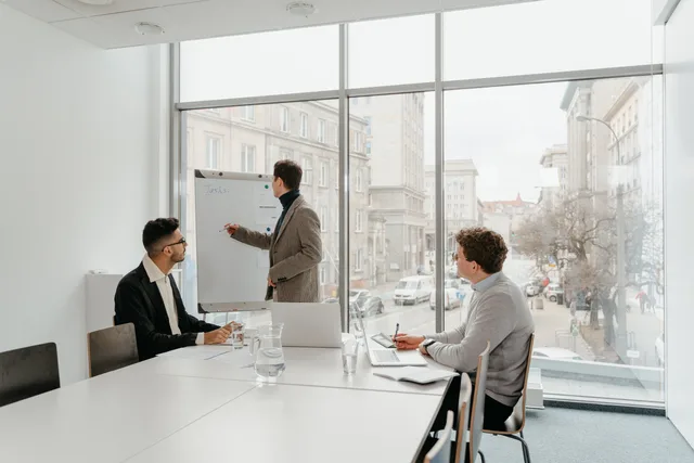 Three professionals engaged in a business meeting in a bright conference room. Jämför CRM-system efter krav och behov